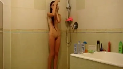 Étudiante mince prend une douche pendant qu'un type la filme